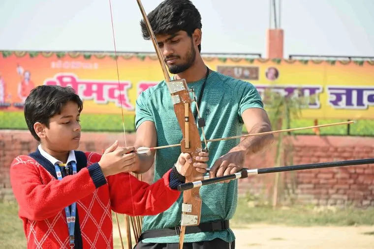 Students of Sunbeam School Ballia on the archery line, four at full draw with a coach behind them.