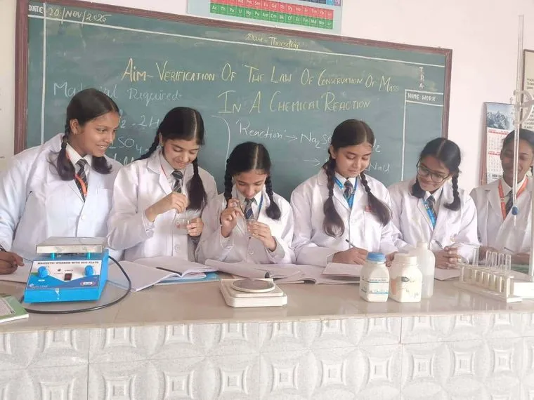 Students of Sunbeam School Ballia in lab coats at a chemistry practical, verifying the law of conservation of mass.