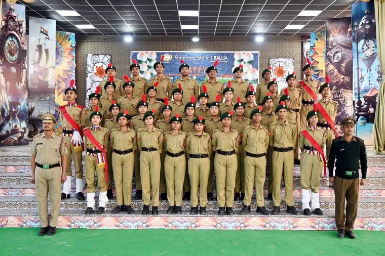 Students of Sunbeam School Ballia assembled for a group photograph under the portico, in school blazers and lanyards, with their teachers standing at either end of the rows.